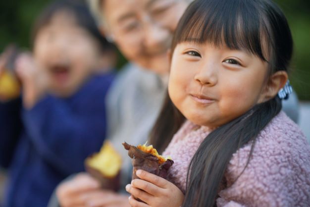 焼き芋を食べて笑顔になっている女の子